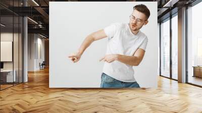 energetic satisfied handsome young european male in casual white t-shirt dancing tilting right and m Wall mural