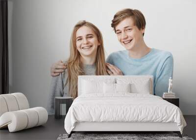 Everoyone think we siblings, but we date. Positive best friends with fair hair and braces, hugging and smiling broadly, being happy to rely on each other. Brother made great present to impress sister Wall mural