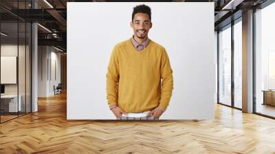 Friendly good-looking guy waiting for girlfriend to dress up. Portrait of good-looking african-american with afro hairstyle in stylish yellow pullover holding hands in pockets, smiling casually Wall mural