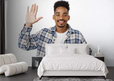 Greeting. Smiling friendly african american guy tell his name, raise hand and put arm on chest, introduce himself, say hello, making promise, standing over white background Wall mural