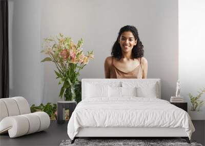 Happy beautiful african female florist smiling looking at camera at workplace in flower shop. Copy space. Wall mural