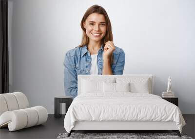 Happy successful woman standing in casual outfit, smiling pleased at camera and looking confident, standing against white background Wall mural