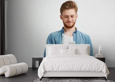 happy young handsome man smiling looking at phone surfing internet browsing web over white backgroun Wall mural