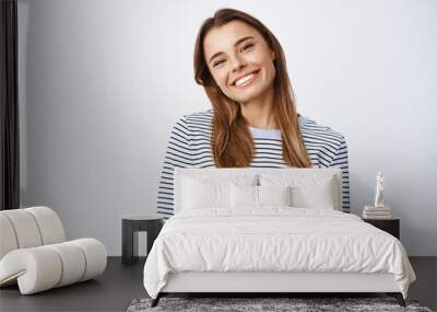 Image of cheerful good-looking woman tilt head and smile at camera friendly, looking joyful and carefree, standing in casual clothes against white background Wall mural