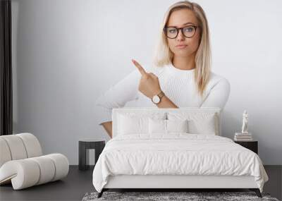 Irritated woman being annoyed waiting boyfriend pointing angry and questioned at upper left corner lifting eyebrows pursing lips bothered demanding answers standing bossy and moody over white wall Wall mural