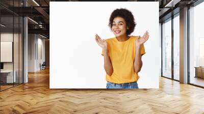 Oops. Smiling silly black girl showing shrugging pose and looking guilty, standing in yellow tshirt over white background Wall mural