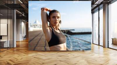 Picture of young beautiful fitness girl makes sport exercises with sea coast on background Wall mural