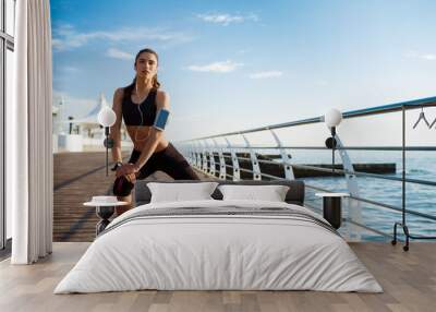 Picture of young fitness girl who makes sport exercises with sea coast on background Wall mural