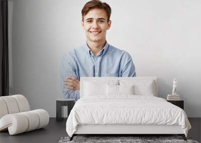 Portrait of handsome young man in casual blue shirt. Boy smiles for the camera expressing happiness and joy. His cute classmate finally agreed to go to prom with him. Friends will be jealous Wall mural