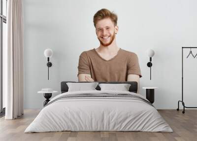 Portrait of happy cheerful young man with beard smiling looking at camera with crossed arms over white background. Wall mural