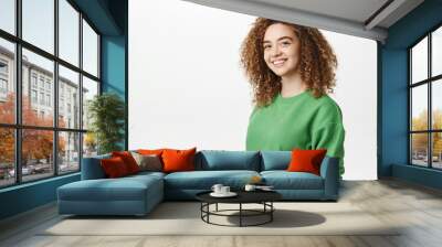 Portrait of modern happy curly girl with white smile, cheerful face expression, standing in green clothes against white background, isolated Wall mural