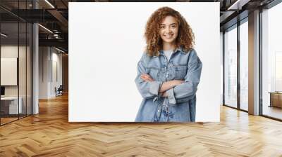 Portrait of modern stylish girl with curly hair smiling, standing in casual outfit. Happy young woman posing against white background Wall mural