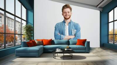 Portrait of young handsome man in jean shirt smiling looking at camera with crossed arms over white background. Wall mural