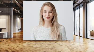 Pretty smiling joyfully female with fair hair, dressed casually, looking with satisfaction at camera, being happy. Studio shot of good-looking beautiful woman isolated against blank studio wall. Wall mural