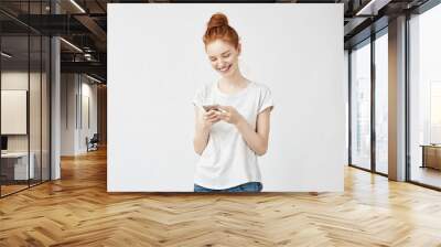 Sincere beautiful redhead girl smiling looking at phone. Wall mural