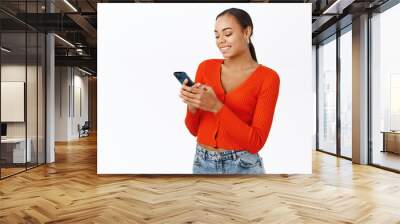 Smiling modern woman using mobile phone, chatting in app, standing in red blouse over white background Wall mural