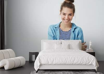 Studio shot carefree tender attractive young confident woman hair combed hairbun smiling, laughing having fun holding smartphone looking camera delighted grinning joking around, white background Wall mural