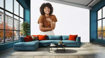 Studio shot of cute african american woman with afro hairstyle in trendy summer outfit having fun laughing out loud from joy and funny joke gesturing with palm chuckling and smiling carefree at camera Wall mural