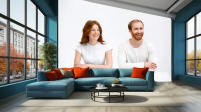 Tenderless redhead girl and boy sitting at white desk Wall mural