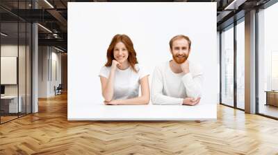 Tenderless redhead girl and boy smile  sitting at white desk Wall mural