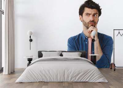 Thoughtful, serious-looking handsome bearded guy, look away pouting pensive, touching chin, thinking, making choice or imaging plan, standing white background pondering how solve situation Wall mural