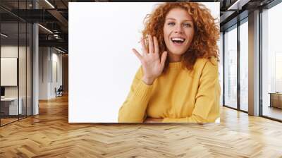 Waist-up cheerful, smiling redhead curly woman silly and coquettish grinning as waving her palm, greeting friend, say hi or hello, leave party and tell everyone goodbye over white background Wall mural