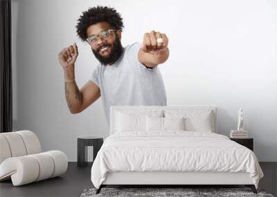 Yo join me in dance competition. Portrait of happy enegized good-looking african american guy in glasses with ring and pierced nose smiling pulling fist towards camera while dancing, shaking hands Wall mural