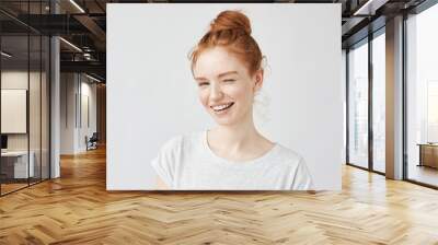 Young playful beautiful girl with foxy hair smiling winking looking at camera. Isolated on white background. Upbeat Wall mural