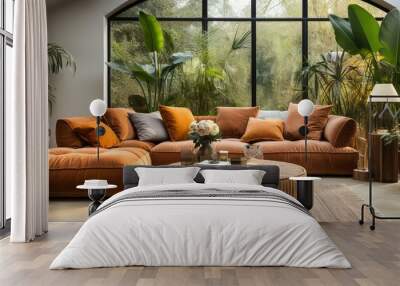 A beige velvet sofa adorned with terra cotta cushions, nestled among lush houseplants. A wooden round coffee table stands nearby next to an ottoman, all placed on a cozy knitted rug. Wall mural