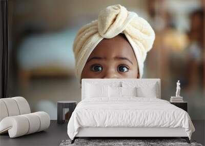 A baby wrapped in a towel smiles at the camera. Wall mural