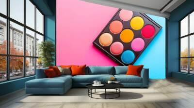 A colorful eyeshadow palette is placed on a pink and blue background. Wall mural