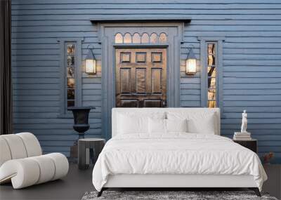 A wooden door on a blue colonial American house with sunset light Wall mural