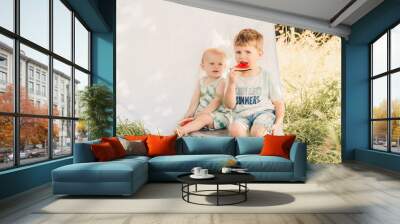 Two brothers sitting in a field on a summers day eating watermelon Wall mural