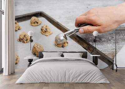 Hand of male baker scooping raw oatmeal raisin cookie dough with scoop on cookie sheet with baking paper, traditional and most popular American biscuit recipe made of flour, sugar, eggs, rolled oats Wall mural