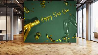 HAPPY NEW YEAR 2025 Silvester Sylvester New Year's eve greeting card with text - Golden champagne bottle, champagne or sparkling wine glasses and ribbons, isolated on green table background, flat lay Wall mural