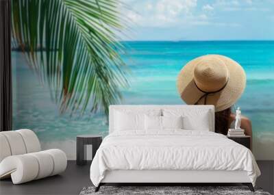 Summer vacation travel holiday tourism background - Young pretty woman in a straw hat looking to the beach ocean, blue sky and palm tree leaves Wall mural