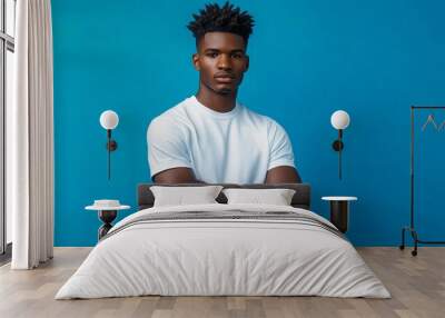 A bust shot of confident young black male fashion model, posing with athleisure clothes against a vibrant cobalt blue studio background Wall mural