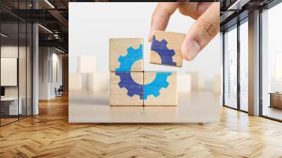 Hand putting the last piece of wooden blocks with the gear icon. Team work, unity, partnership or integration concept. Wall mural