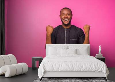 Young African man wearing and black native attire jubilating over something he saw Wall mural