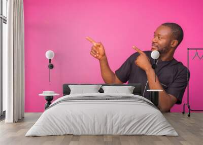 young african man wearing and black native attire pointing at something at his top right corner Wall mural