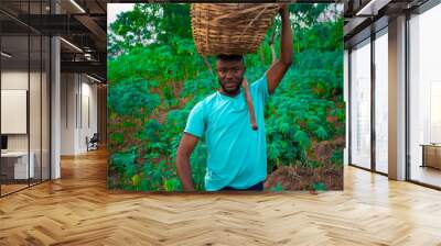 young black happy farmer carrying a basket on his head  Wall mural