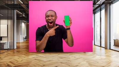 young black happy man holding out his smartphone and pointing at it Wall mural