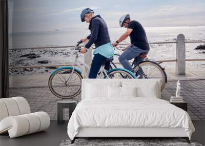 Bike, cycling and fitness with a senior couple on the promenade, riding eco friendly transport for travel. Bicycle, beach or exercise with a mature man and woman cyclist out on a ride for tourism Wall mural