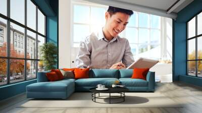 Asian man, tablet and marketing manager doing online planning in a modern office while reading email communication. Happy startup businessman with smile, technology and social media project at work Wall mural