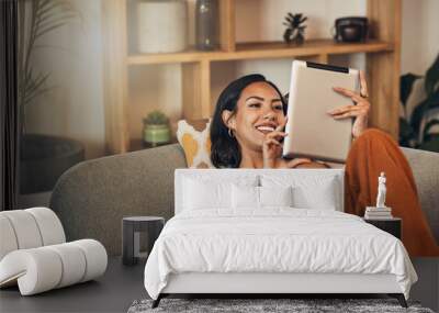 Woman relax on couch with tablet, online streaming with internet and reading ebook or watching film at home. Happy female person with technology, subscription and mobile app with break in living room Wall mural