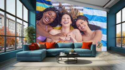 Friends, beach and women with heart for love and support on vacation, travel or holiday in summer. Above group together on towel for tropical, funny or comic time together with diversity and hands Wall mural