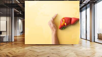  Hand hold liver organ with red yellow awareness ribbon on yellow background for banner of World Hepatitis day on July 28th Wall mural