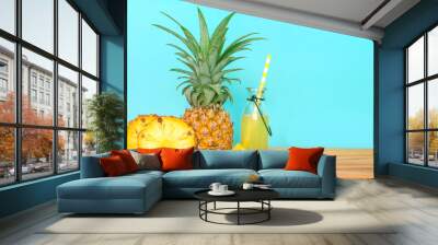 The Bottles of pineapple juice with sliced pineapple fruit on wooden table with fresh blue background , summer fruit drink concept Wall mural