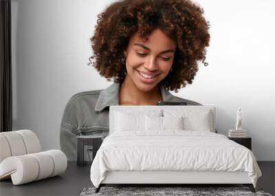 A portrait of a young African American black woman with curly hair looking at her mobile phone and smiling, isolated in a transparent background. Cut out or PNG. Wall mural