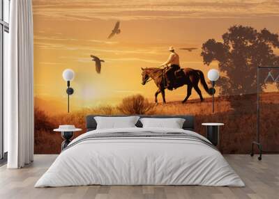 A cowboy on his horse with crows flying above.  A cowboy takes a look to his right and see three large crows flying towards him. Wall mural